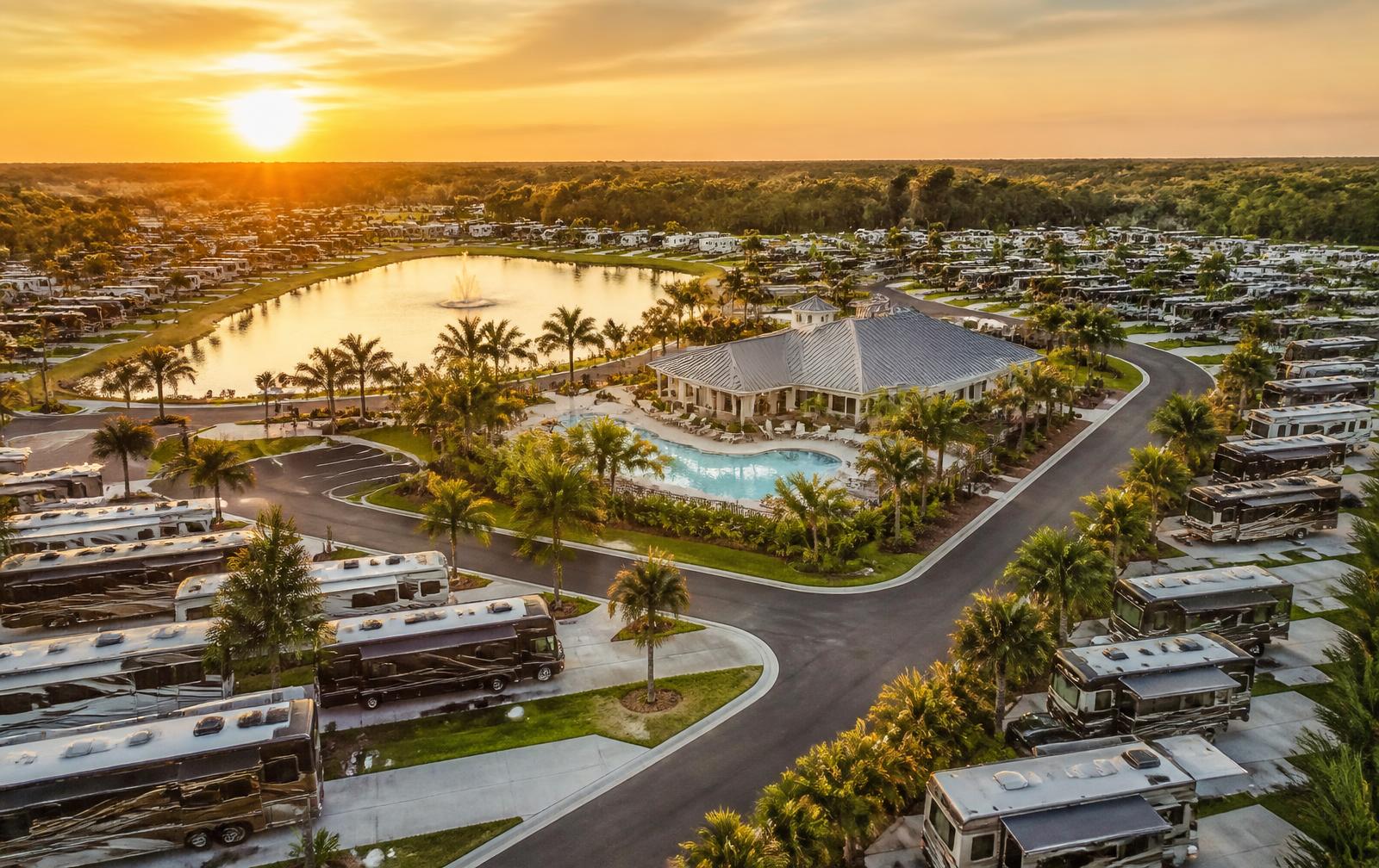 Aerial view of a Florida RV resort with paved sites, a lake and clubhouse at sunset